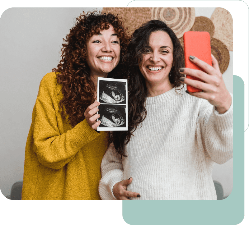 Two women smiling with ultrasound photo.